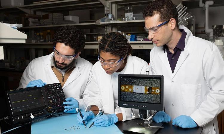 Lead study author Ramy Ghanim (left) and co-author Joy Jackson test an small implantable device alongside Assistant Professor Alex Abramson. In a new Science paper, they describe a networking system that connects therapeutic implants and wearable devices by using the body's natural conductivity to send tiny signals.
