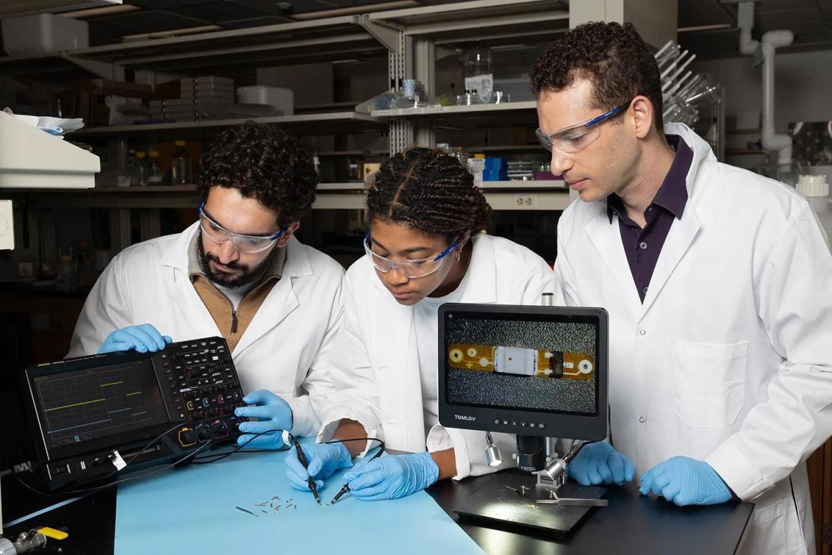 Lead study author Ramy Ghanim (left) and co-author Joy Jackson test an small implantable device alongside Assistant Professor Alex Abramson. In a new Science paper, they describe a networking system that connects therapeutic implants and wearable devices by using the body's natural conductivity to send tiny signals.